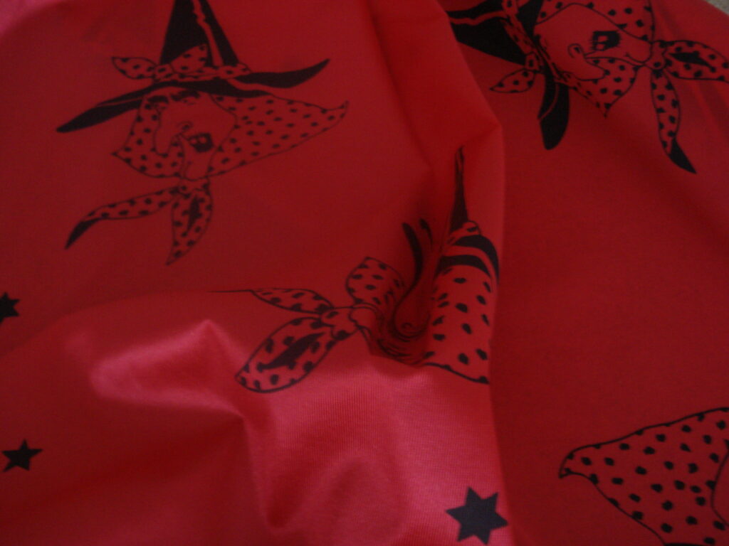 Tejido en rasete f/rojo dibujo caras bruja