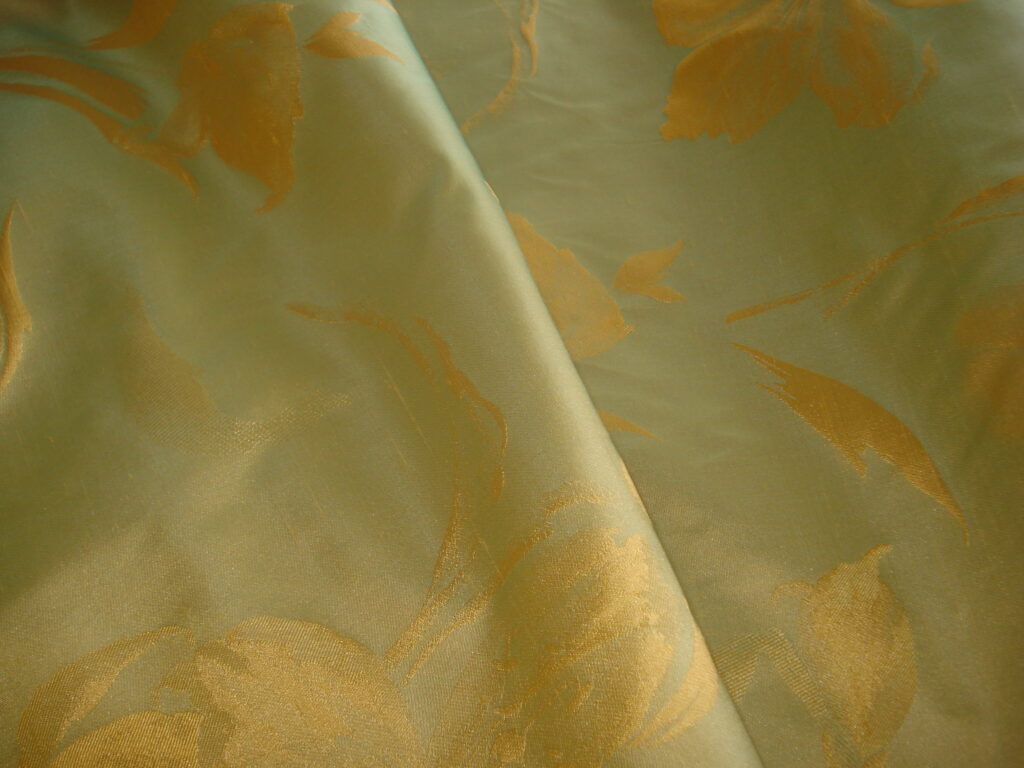 Tejido en seda salvaje f/ verde helecho claro con dibujo dorado, ancho 1.50mts.