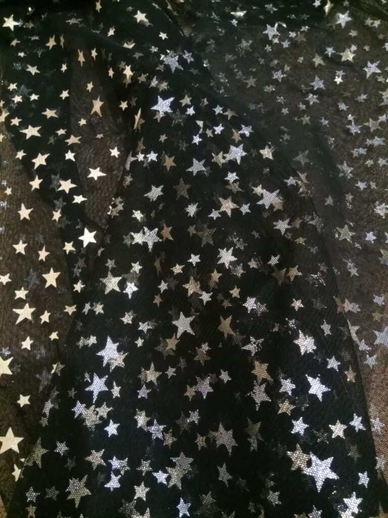 Tejido tul fino c/negro con estrellas doradas y plateadas, ancho 1.54mts.