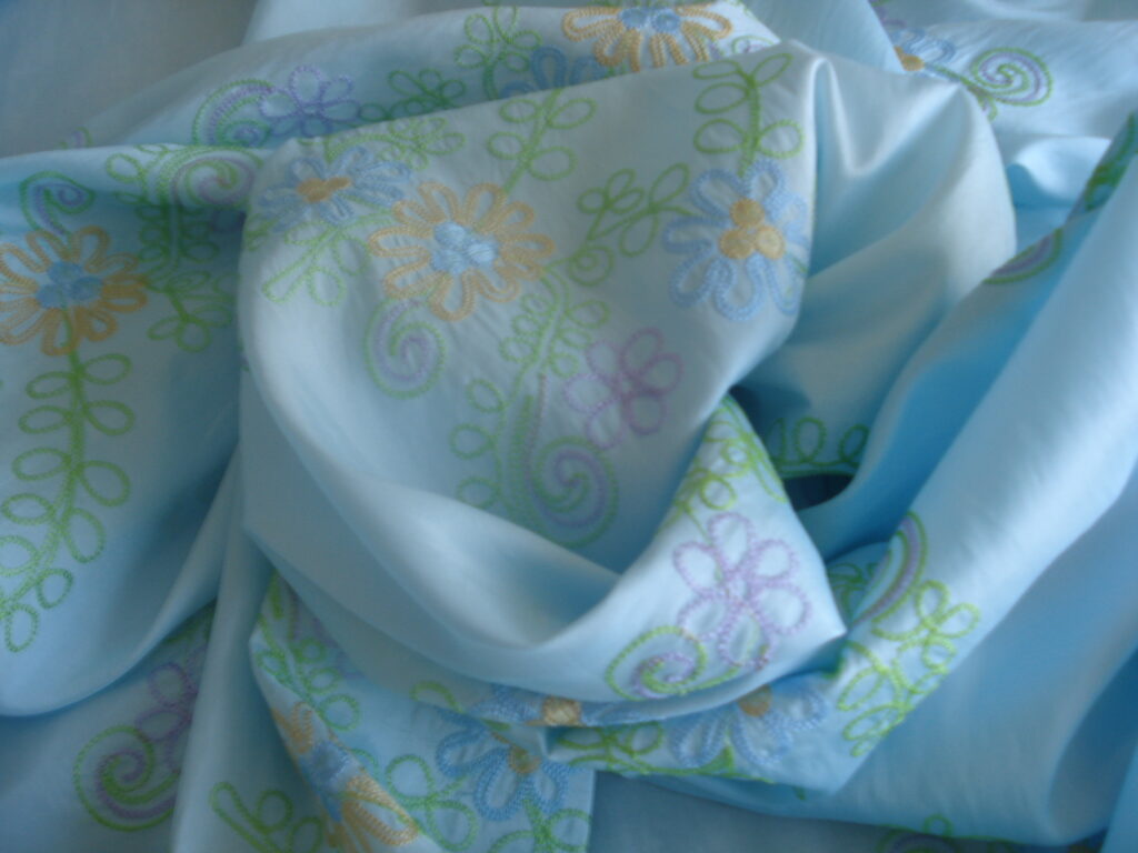 Tejido satinado efecto arrugado f/azul c/flores bordadas, ancho 1,50mts.